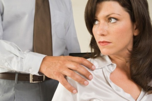 Man touching shoulder of uncomfortable woman co-worker